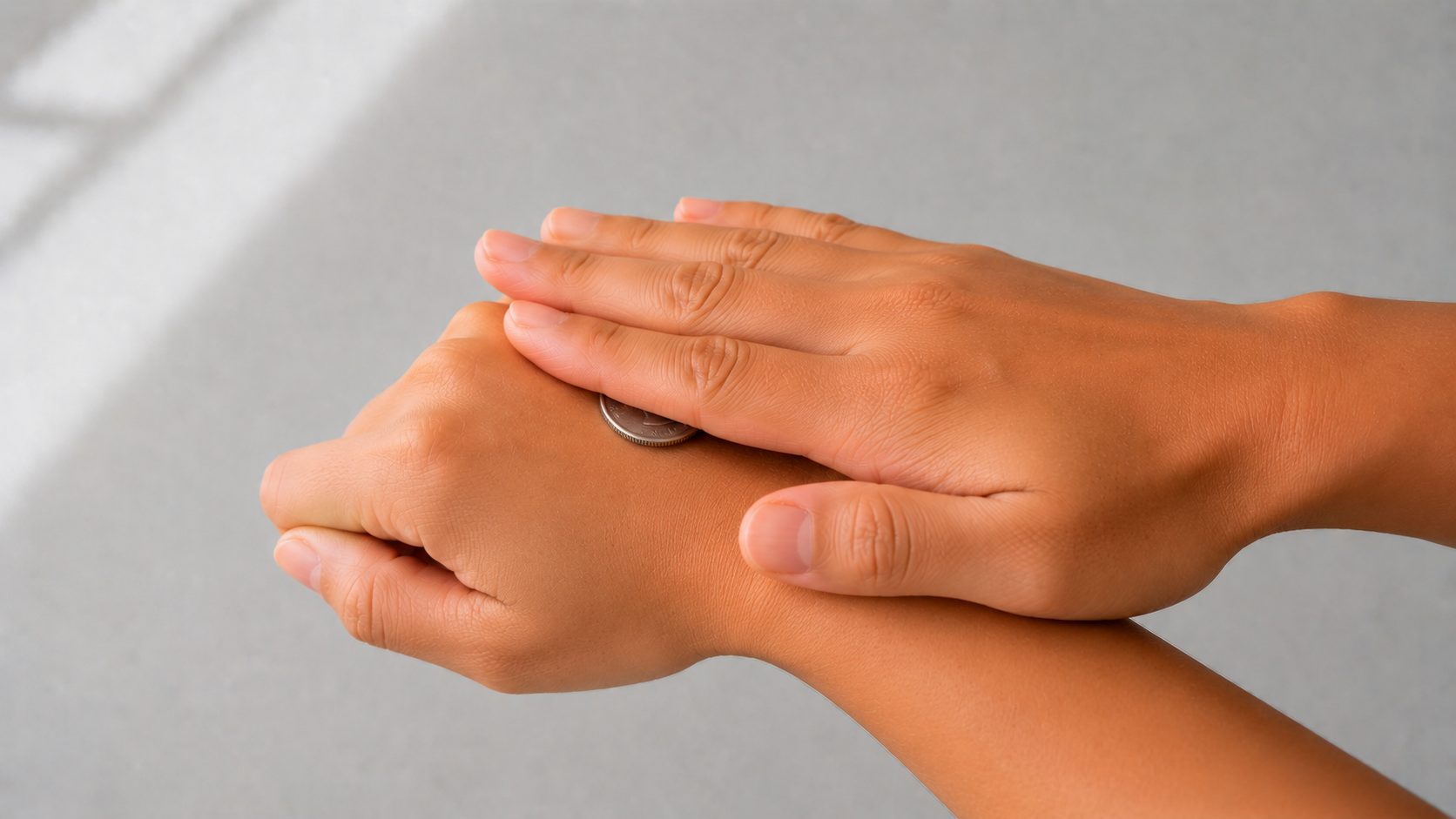 A coin pinned to the back of one hand by the palm of the other — the backhand-slap catch