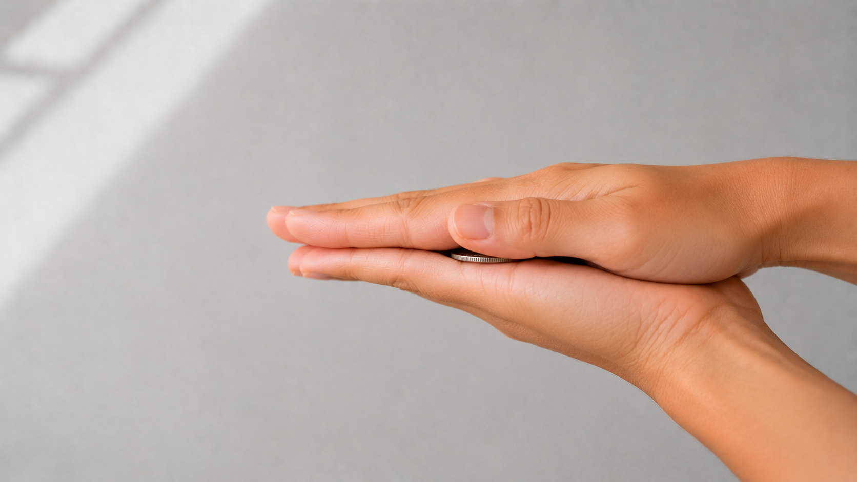 Two palms pressed together horizontally, sandwiching a coin between them