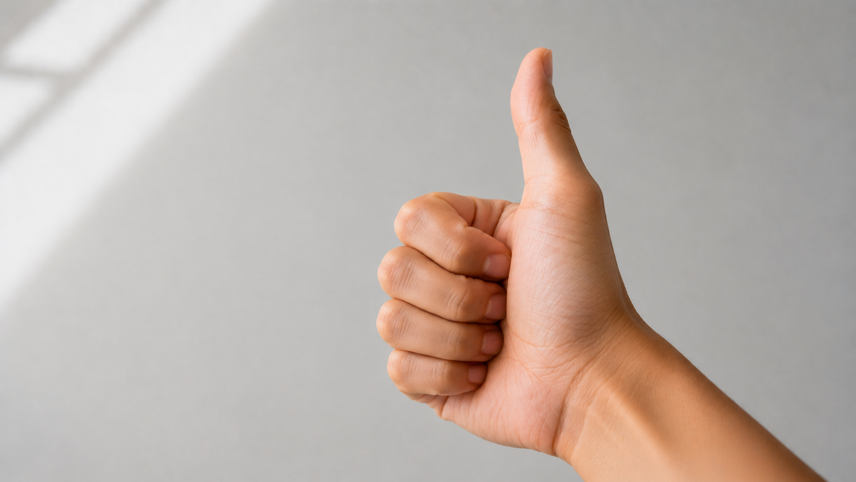 A hand showing a thumbs-up — the starting thumb position for a coin flip