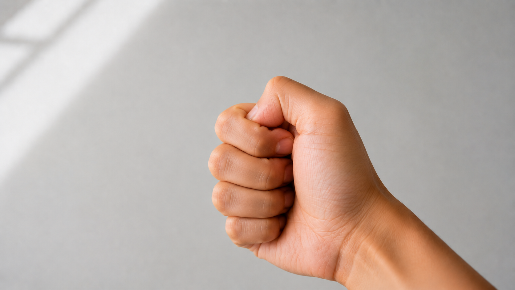Side view of a hand with the thumb tucked under the index finger, ready to flick